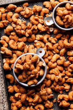 two measuring spoons filled with nuts on top of a tray