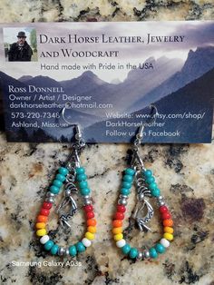 a pair of colorful beaded earrings on top of a marble counter next to a business card