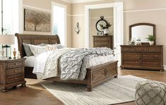 a bedroom scene with focus on the bed and dressers, mirror and nightstand unit