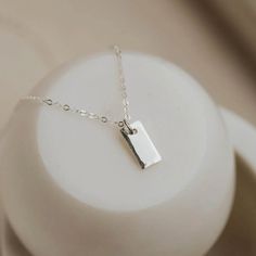 She may be tiny, but she is mighty! We love the versatility of this tiny tag necklace. It’s beautifully hammered edges give her just enough pop and personality. Wear it alone or pair it with multiple chains for a layered look. * tiny 5mm x 10mm rectangle tag. * we hammer just the edges for a subtle detail. * suspended from 16" of our daintiest isla chain. * available in 14kt gold fill + sterling silver. * handmade in Eau Claire, WI. All of our jewelry is handmade to order just for you so each pi Dainty Sterling Silver Charm Necklace With Rectangular Pendant, Silver Rectangular Charm Necklace With Delicate Chain, Sterling Silver Rectangular Charm Necklaces For Everyday, Dainty Rectangular Pendant Bar Necklace For Everyday, Minimalist Rectangular Charm Necklace For Everyday, Minimalist Everyday Rectangular Charm Necklaces, Minimalist Everyday Rectangular Charm Necklace, Everyday Minimalist Rectangular Charm Necklace, Everyday Charm Necklace With Delicate Rectangular Pendant