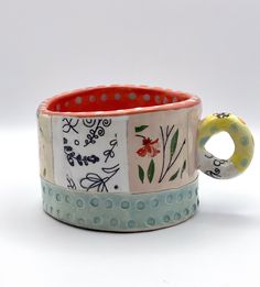 a close up of a ceramic cup on a white surface with polka dots and flowers