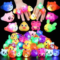 a child's hand surrounded by many colorful plastic toy animals and small glowing lights