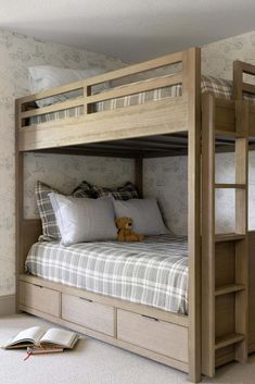 a bunk bed with drawers underneath it and a teddy bear on the floor next to it