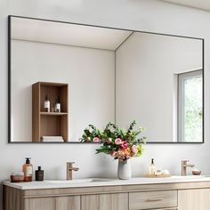 a bathroom with two sinks and a large mirror on the wall above it that has flowers in a vase