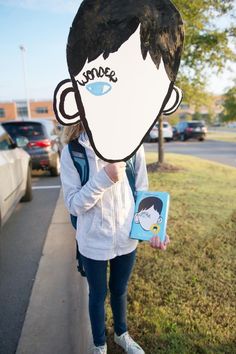 a woman holding up a cardboard cut out of a man's face