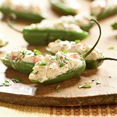 several green peppers with crab salad on them sitting on a cutting board, ready to be eaten