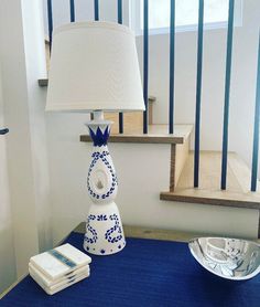 a blue and white table with a lamp on top of it next to a bowl