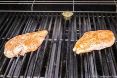 two pieces of chicken are cooking on the grill