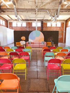 rows of colorful chairs are arranged in an empty room with a large screen on the wall