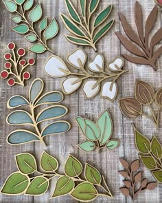 some cut out leaves and berries on a wooden table with white paper in the background