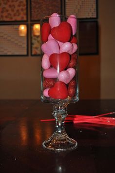 a glass filled with candy hearts on top of a table