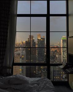 a bedroom with a view of the city from it's large window sill