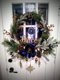 a wreath with the word peace on it hanging in front of a door decorated for christmas