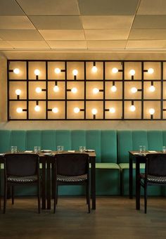 a restaurant with green booths and wooden tables in front of a large window that has lights on it