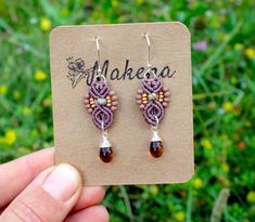 a pair of earrings with beads on top of a piece of paper in front of some grass