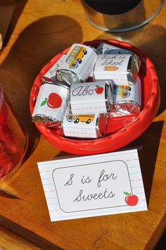 a red bowl filled with lots of candy next to a sign that says s is for sweets