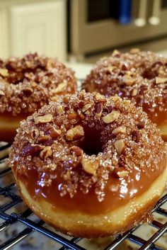 three glazed donuts sitting on top of a cooling rack