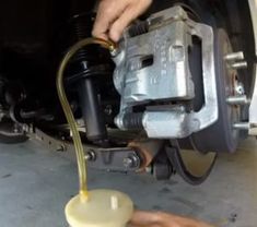 a man is pouring oil on a car's brake assembly unit to change it