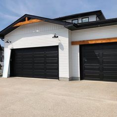 a white house with two black garage doors