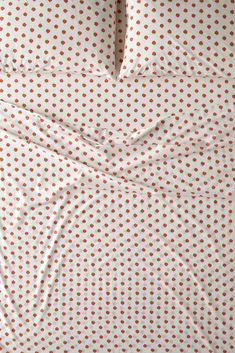 an unmade bed with white and red polka dot sheets