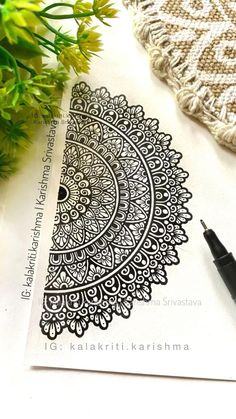 an intricate design is shown on top of a piece of paper next to some flowers