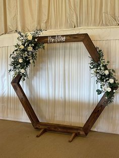 a wooden hexagonal frame with flowers and greenery on the side for a wedding ceremony