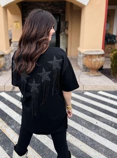 This Ain't Texas Fringed Star Sequin Patch Tee in Black Sparkle and shine in this edgy black tee featuring beaded star patches with metal fringe accents! With a relaxed fit, you'll be comfortable while standing out from the crowd. This tee ain't your average Texas shirt! Beaded Star Patches with METAL FRINGE! How COOL! 🤤 Relaxed Fit. Hand Wash Cold. Lay Flat To Dry. If You Are In-Between Sizing, Go With The Smaller of the Two Sizes. Model is Wearing the Size Small. 100% Cotton Small (2-6) Mediu Trendy Short Sleeve T-shirt With Fringe, Trendy Fringe Short Sleeve T-shirt, Trendy Short Sleeve Fringe T-shirt, Black Crew Neck Top With Star Patch, Trendy Black Top With Star Patch, Black Crew Neck T-shirt With Star Patch, Black Embellished T-shirt For Party, Embellished Short Sleeve T-shirt For Night Out, Trendy Fringe Tops For Night Out