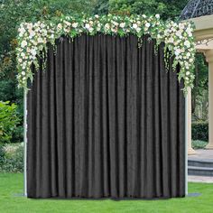 a black curtain with white flowers and greenery on the top is in front of a gazebo