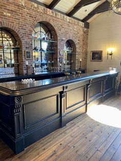 an old fashioned bar in the middle of a room with brick walls and arched windows