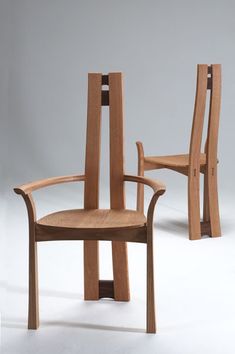 two wooden chairs sitting next to each other on a white surface with no one in it