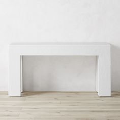 a white table sitting on top of a hard wood floor next to a white wall