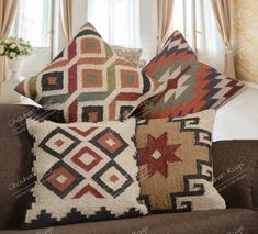 three pillows sitting on top of a brown couch