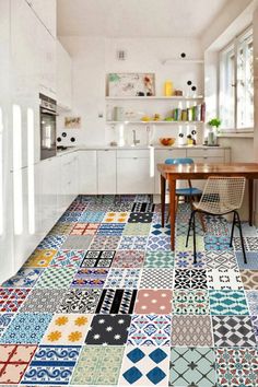 a kitchen with colorful tiles on the floor and walls, along with a dining room table