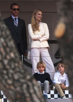 two men and one woman are standing on the sidelines with their arms crossed as they look at something