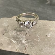 a three stone ring sitting on top of a piece of rock with ice crystals around it