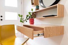 a wooden desk with a mirror on the wall above it and a yellow chair next to it