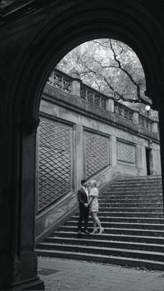 two people are standing on the steps in front of an archway