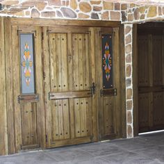 two wooden doors in front of a stone wall