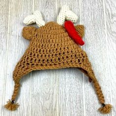 a crocheted bear hat with a red nose laying on top of a wooden floor