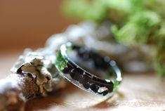 Black Tourmaline Resin Ring with Real Moss and 925 Silver flakes. A smooth round band made with Black Tourmaline stones, real moss and 925 silver flakes in clear Eco resin. Black Tourmaline is also a powerful grounding stone, electrical in nature, providing a connection between Earth and the human spirit. You can choose the shape of the ring you prefer from the drop down menu, I can custom your ring in a flat square thin shape or in a smooth rounded band shape. I love to borrow rich seemingly ch Black Ring For Men, Moss Ring, Mens Black Ring, Black Tourmaline Stone, Black Tourmaline Ring, Ring Man, Eco Resin, Black Ring, Resin Ring