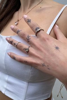 a woman's hand with tattoos on it and two fingers in front of her