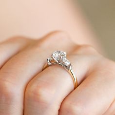 a close up of a person's hand holding a diamond ring