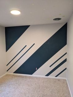 an empty room with black and white stripes painted on the wall, carpeted floor