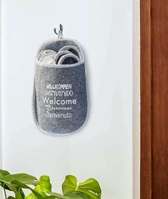 a potted plant sitting next to a white wall with a welcome sign on it