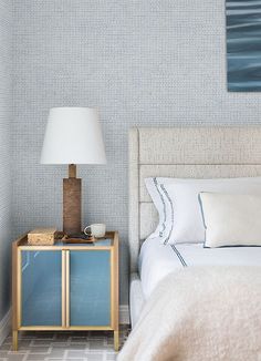 a white bed sitting next to a blue nightstand with a lamp on top of it