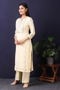 Stand out with this gorgeous mulmul cotton kurta in cream color with cotton stretch pants in a breezy and delicate cream tone featuring sequin and thread embroidery work with gota detailing on neckline. This beautiful mulmul cotton material outfit showcases beautiful sleeves with lace work on it offering a comfortable fit, making this outfit an absolute head-turner at parties. Style this set of kurta with a pair of diamond earrings and solid pumps to finish the look from Pure Elegance. Disclaimer: The actual product may vary slightly from the image. These are custom orders, hence expect slight variation in color, placement of the motif or buta. ESTIMATED DELIVERYBecause this is a custom order, it would take about 4 weeks from the date of purchase. RETURN POLICYThis product is a custom orde Cream Cotton Palazzo Set With Resham Embroidery, Beige Kurta With Cutdana, Unstitched Cream Kurta With Gota Work, Cream Cotton Palazzo Set With Straight Kurta, Beige Unstitched Kurta With Gota Work, Unstitched Beige Kurta With Gota Work, Beige Kurta With Gota Work For Eid, Cream Straight Kurta, Off White Cotton Palazzo Set With Dabka Work