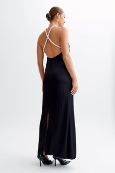 the back of a woman wearing a black evening gown with pearls on her neckline