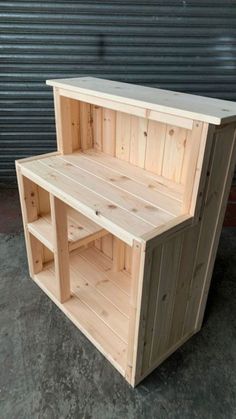 a wooden shelf sitting on top of a cement floor next to a metal garage door