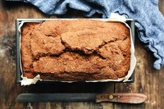 a loaf of bread sitting on top of a wooden table next to a knife and cloth