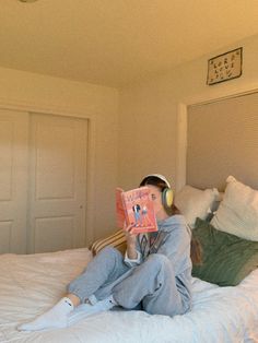 a person laying in bed with headphones on reading a book and listening to music